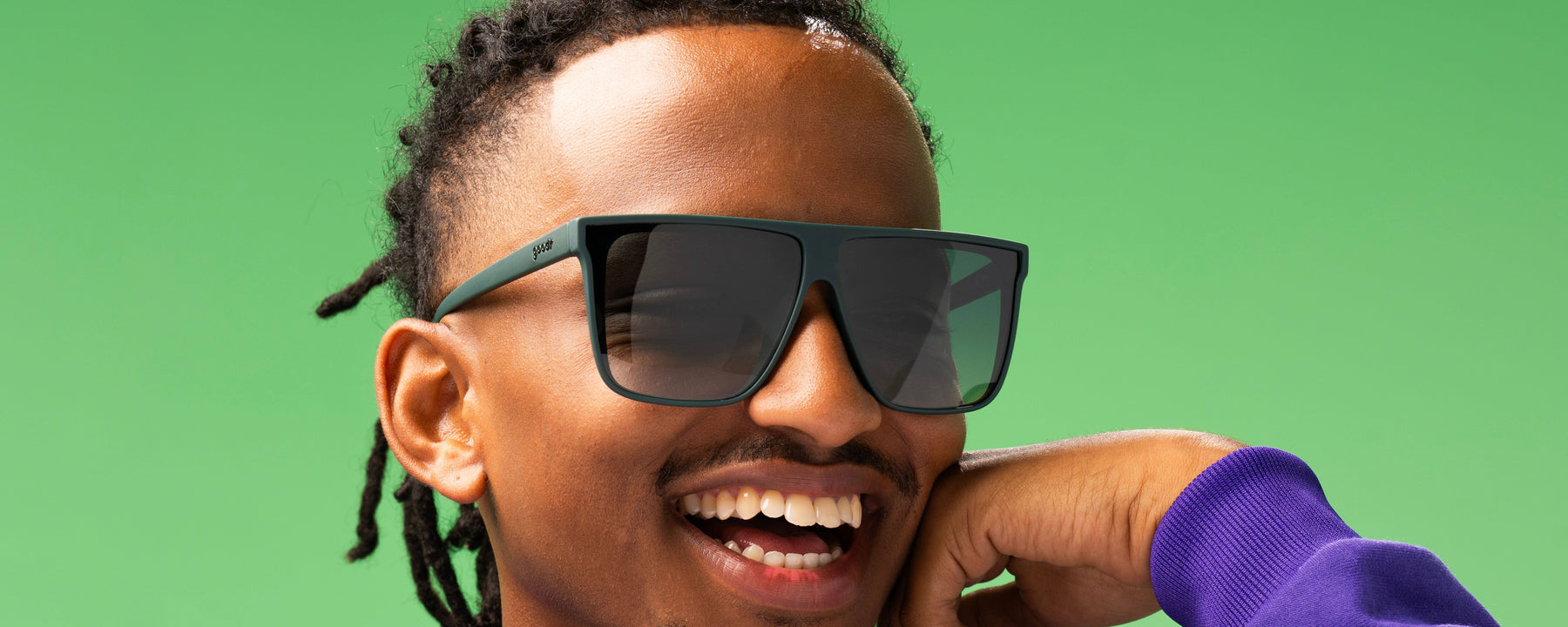 Person smiling wearing dark green goodr sunglasses.