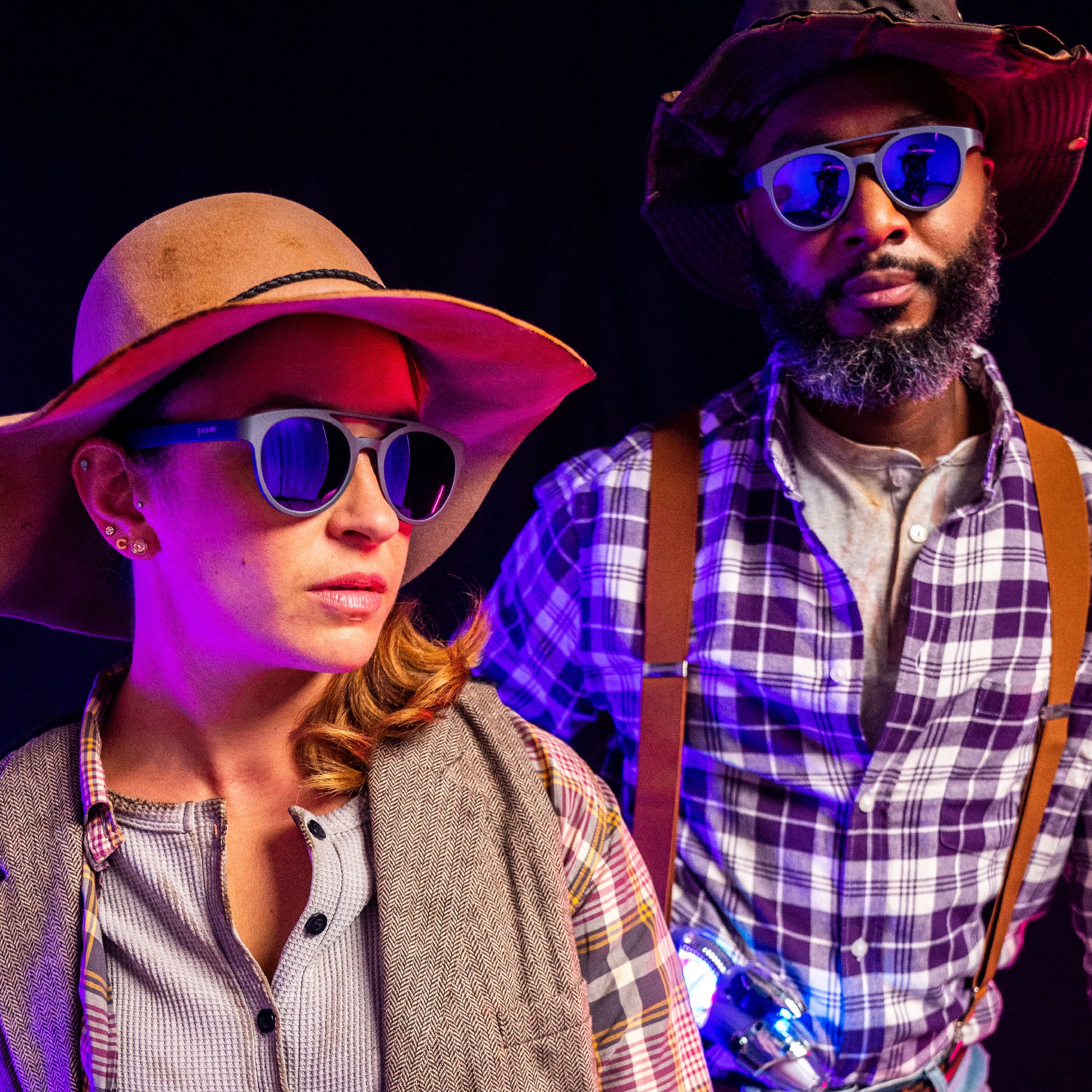 A man and a woman wearing plaid, sun hats, and round sunglasses with dark lenses