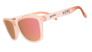 Three-quarter angle view of translucent pink sol rosa sunglasses with reflective champagne gold lenses & ACFC logo.