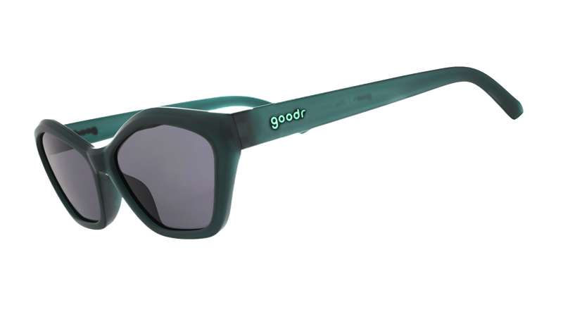 Close-up of a person wearing a striped knit top with brown, navy, cream, and light blue vertical stripes, holding a pair of dark Deco G goodr sunglasses against the chest.