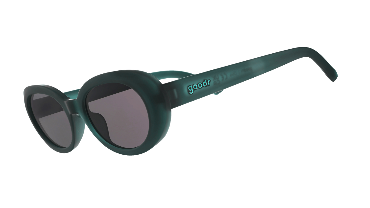 Three-quarter-angle view of translucent dark green Beat G sunglasses with black non-reflective lenses. 