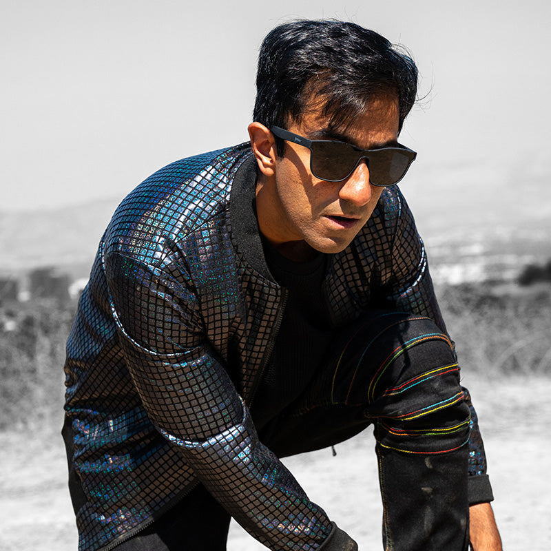 Person wearing sunglasses in a reflective mosaic-patterned jacket leaning forward.