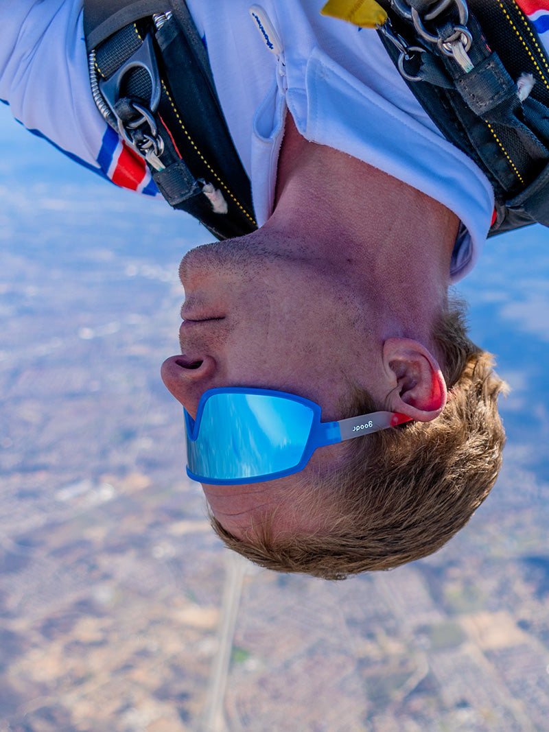 A man skydiving wearing red, white & blue goodr wrap-around sunglasses