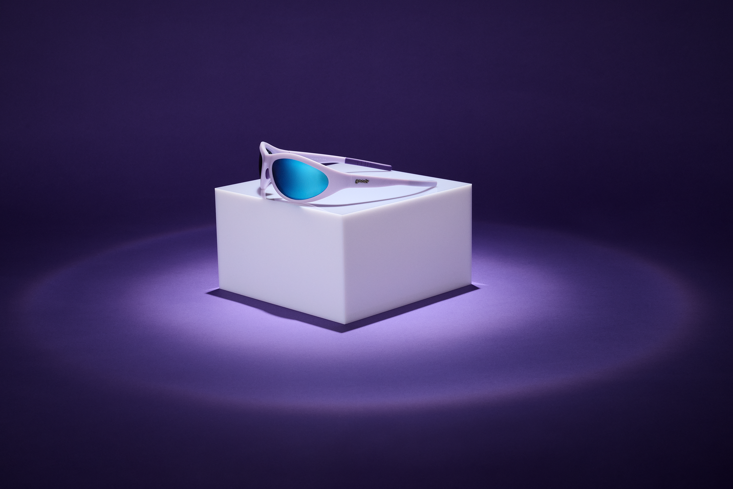 Sleek, futuristic sunglasses with mirrored blue lenses and a white frame, placed on an illuminated white pedestal against a dark purple background.