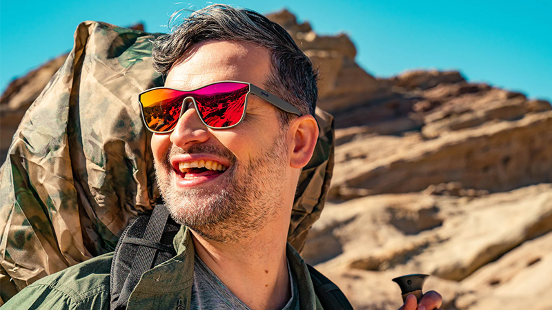 Man wearing pinky orange reflective sunglasses on a mountain