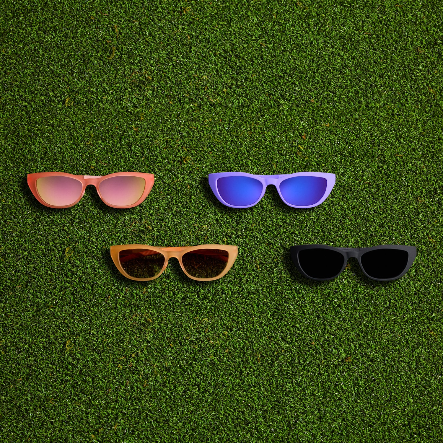 Pink, purple, tan, and black sunglasses on a grassy background.