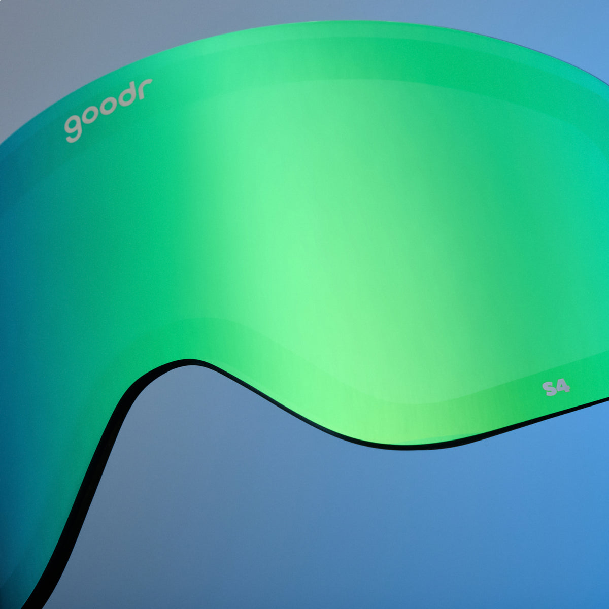 Close-up of bright green mirrored goodr replacement lens against a blue background.