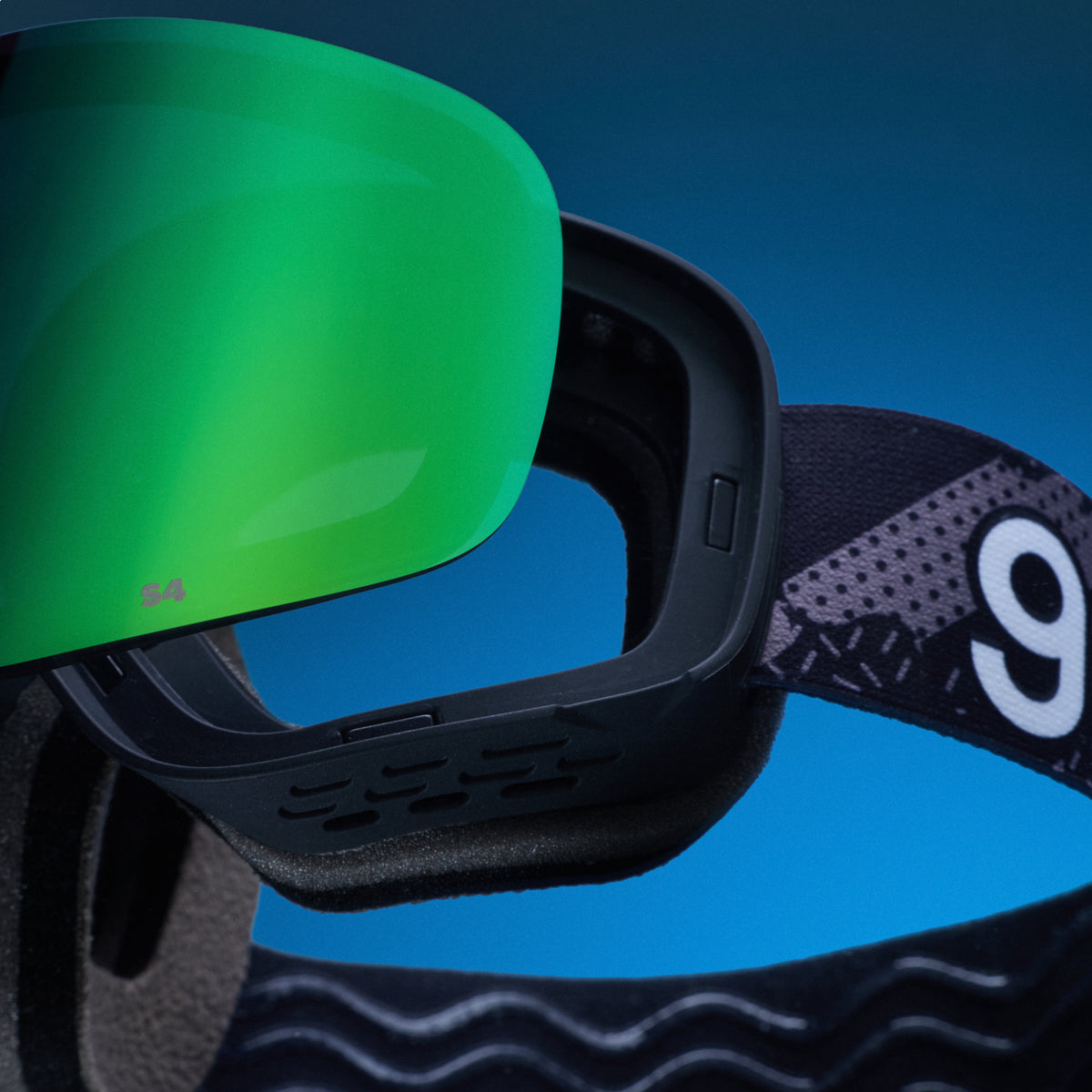 Bright green replacement lens resting above black goodr ski goggles.