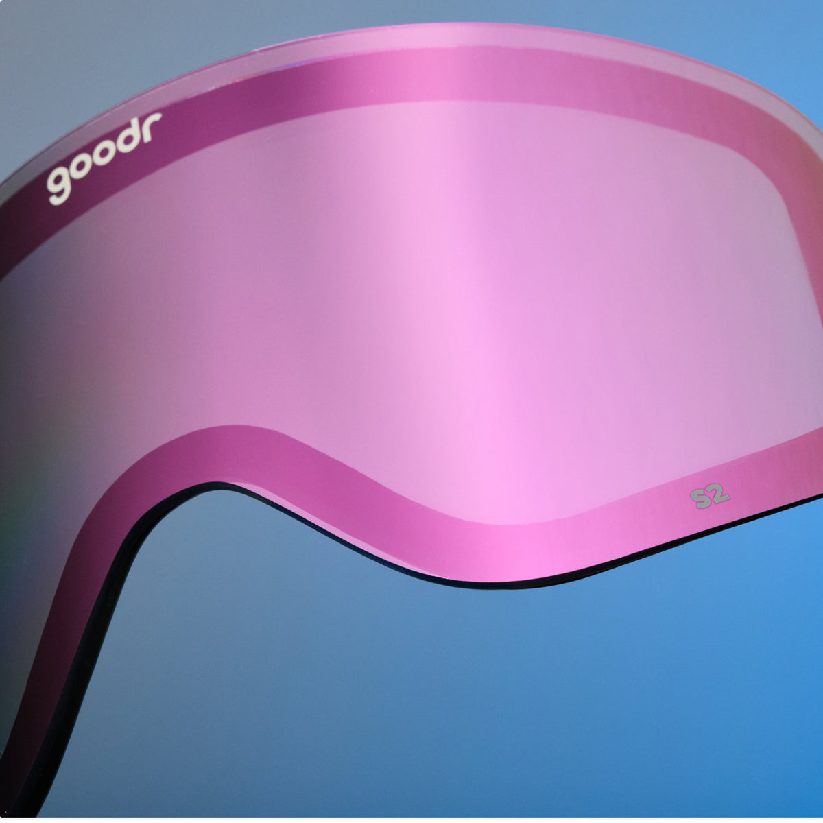 Close-up of pink mirrored goodr replacement lens against a blue background.