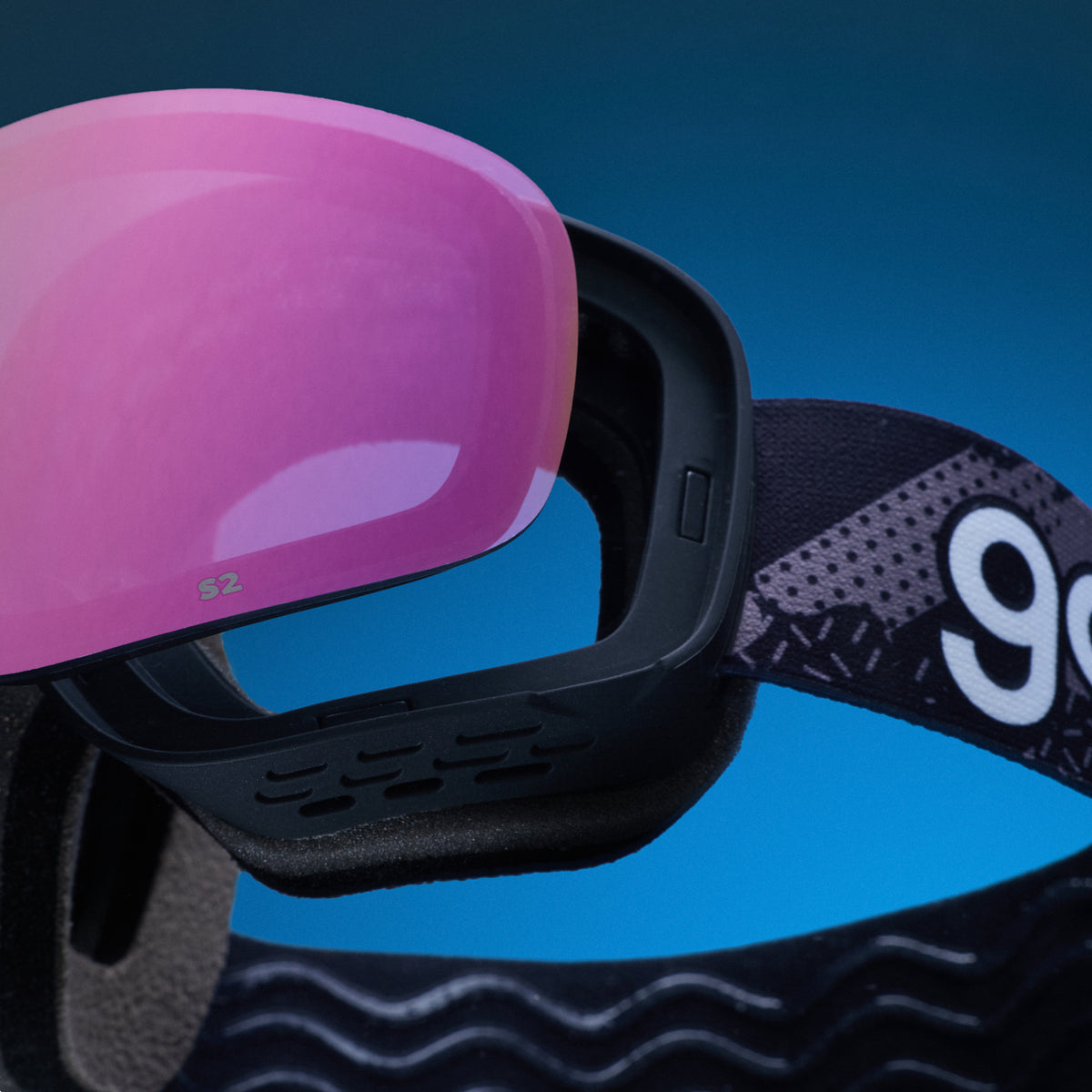 Pink replacement lens resting above black goodr ski goggles.