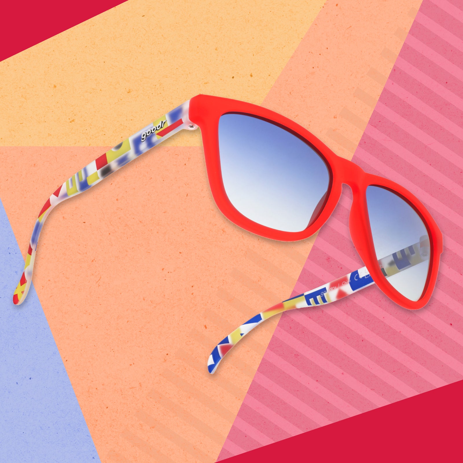 A pair of red sunglasses with multi-colored arms depicting maritime signal flags floating on a geometric background.