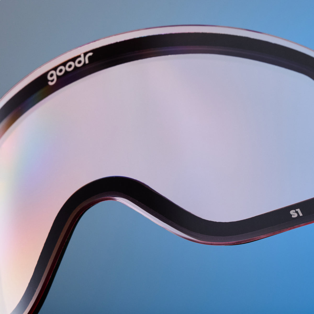 Close-up of pale pink mirrored goodr replacement lens with black trim against blue.