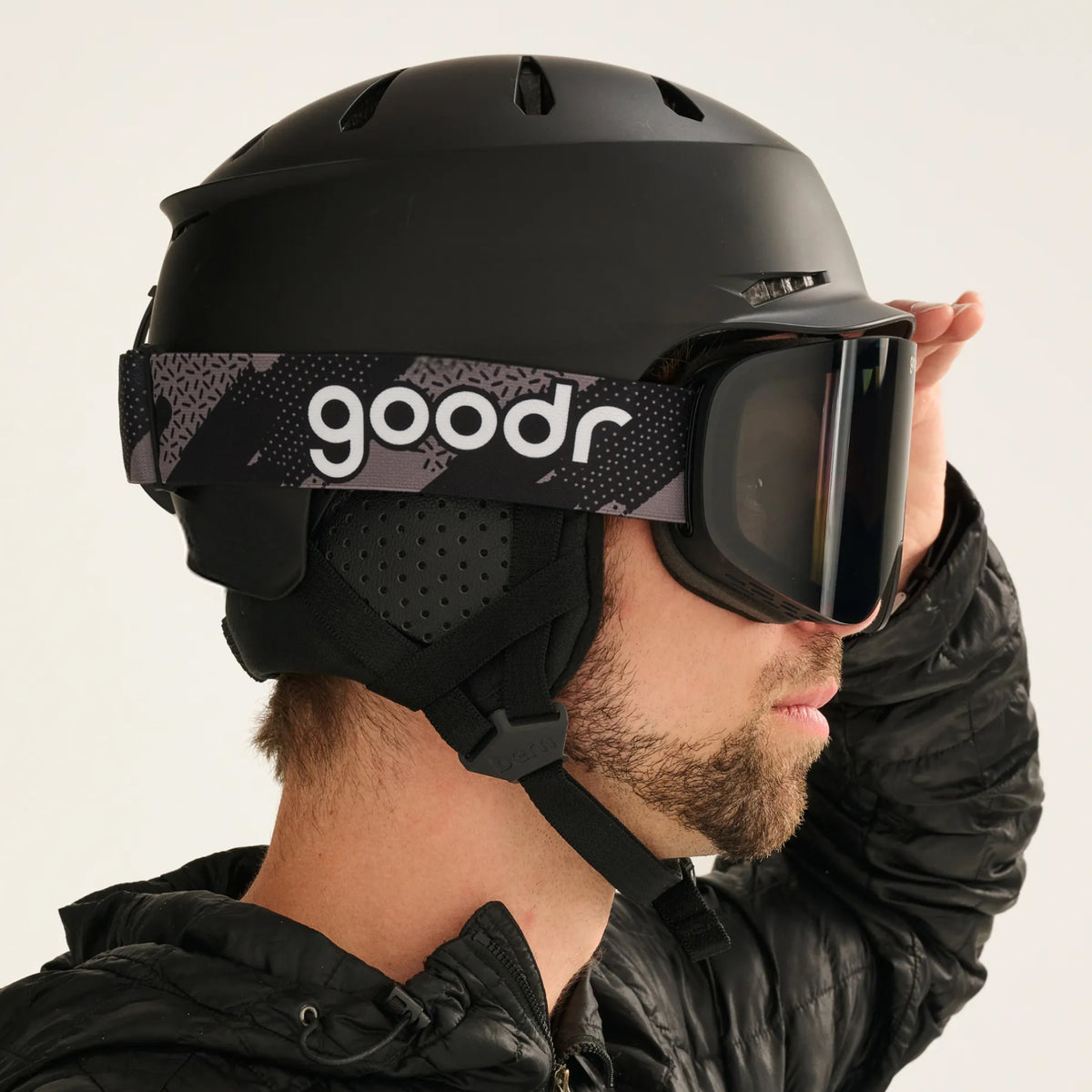 Skier wearing black snow goggles with a patterned goodr strap and black helmet.