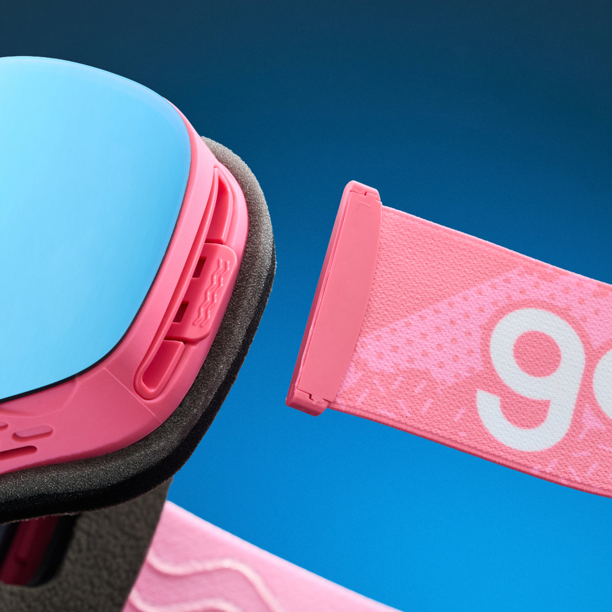 Close-up of blue mirrored snow goggles with a detachable pink goodr strap.