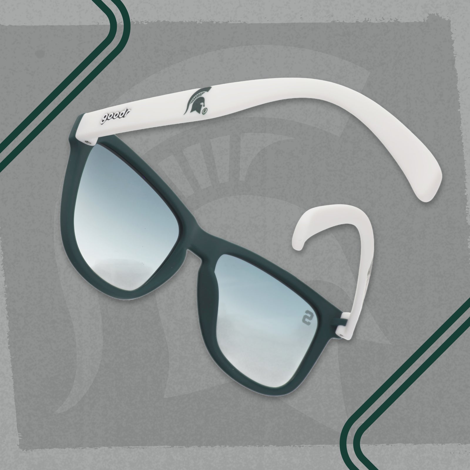 Angled view of Michigan State goodr sunglasses with a dark green frame, white arms, and dark green gradient lenses.