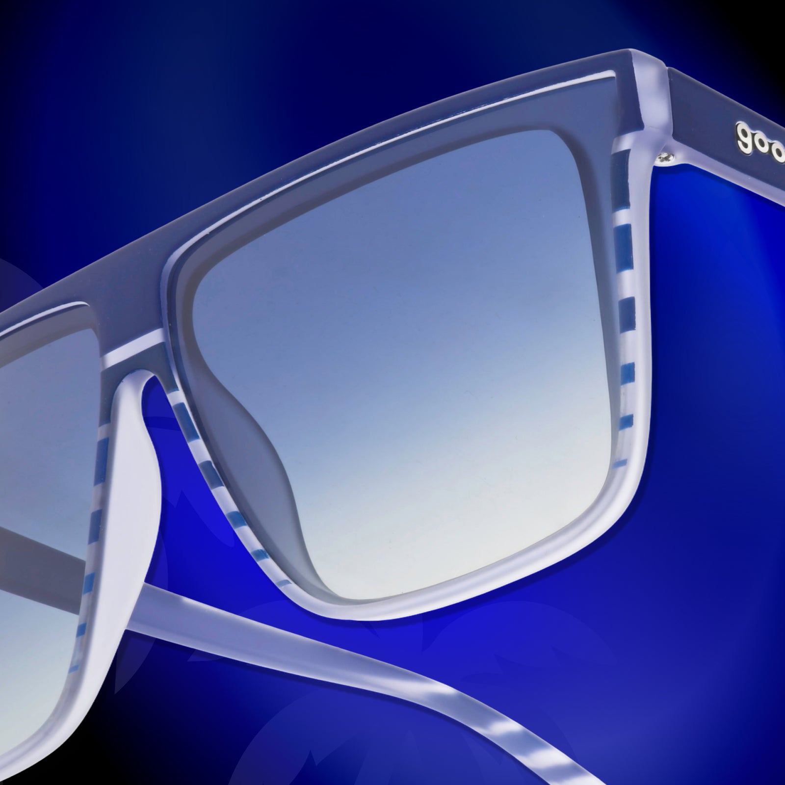 Close-up of the temple of a pair of retro-striped, translucent blue-purple Fly G sunglasses against a vivid blue background.