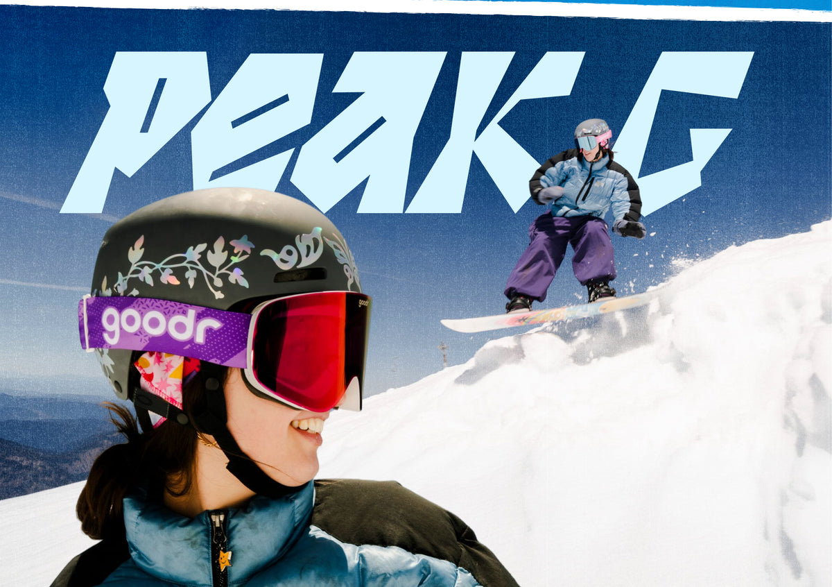 A person in a black ski helmet with floral graphics and red-tinted goggles with a purple strap reading 'goodr' is shown in the foreground, while another person snowboards on a snowy mountain under a blue sky with large 'PEAK C' lettering.